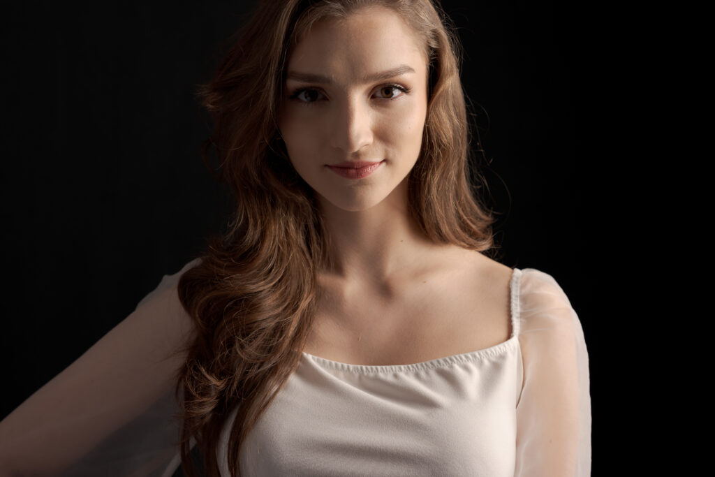 Portret kobiety w białej bluzce na ciemnym tle