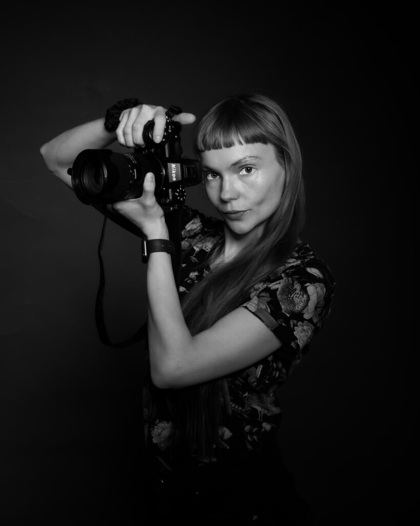 Czarno-biały portret kobiety trzymającej aparat fotograficzny